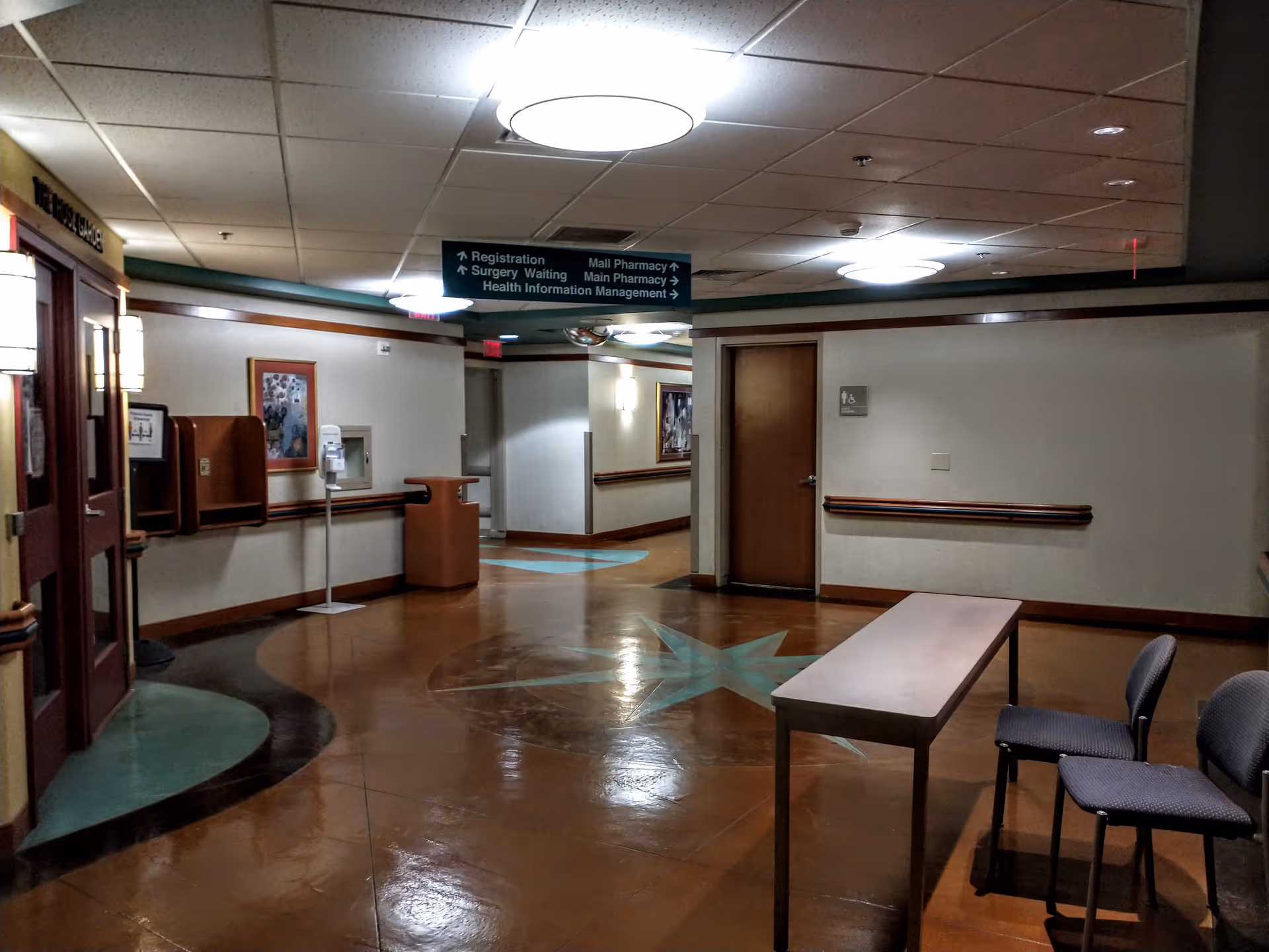 Interior hospital hallway with directional signs and a waiting area.