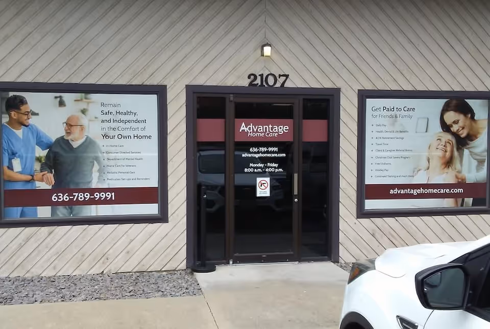 Exterior view of Advantage Home Care building with glass doors and large promotional posters.