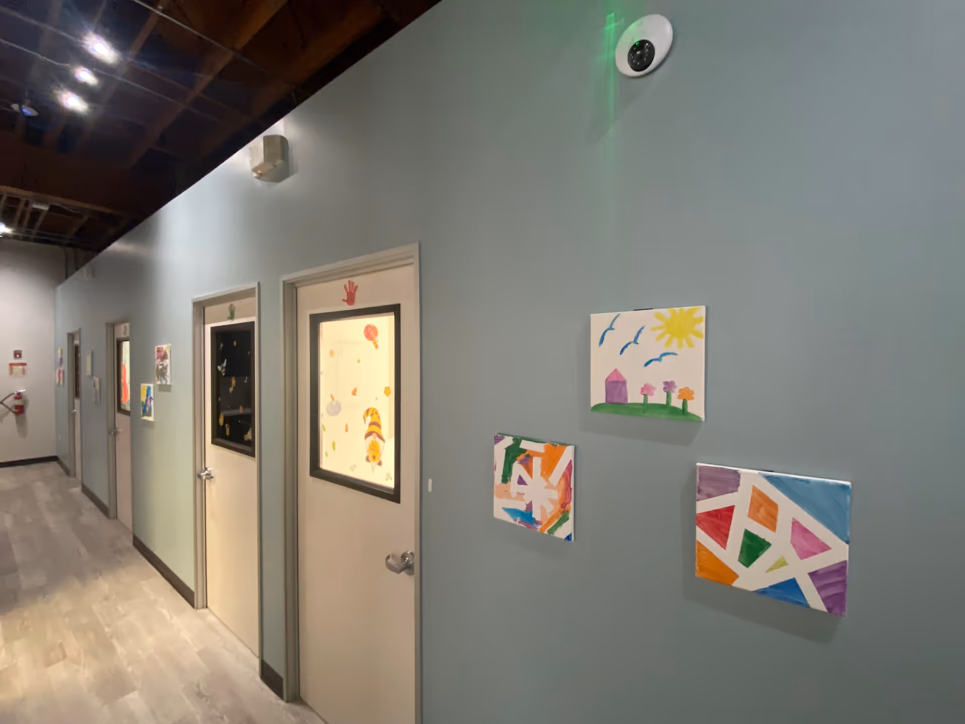 Interior hallway of a senior living facility with doors and colorful children's artwork.
