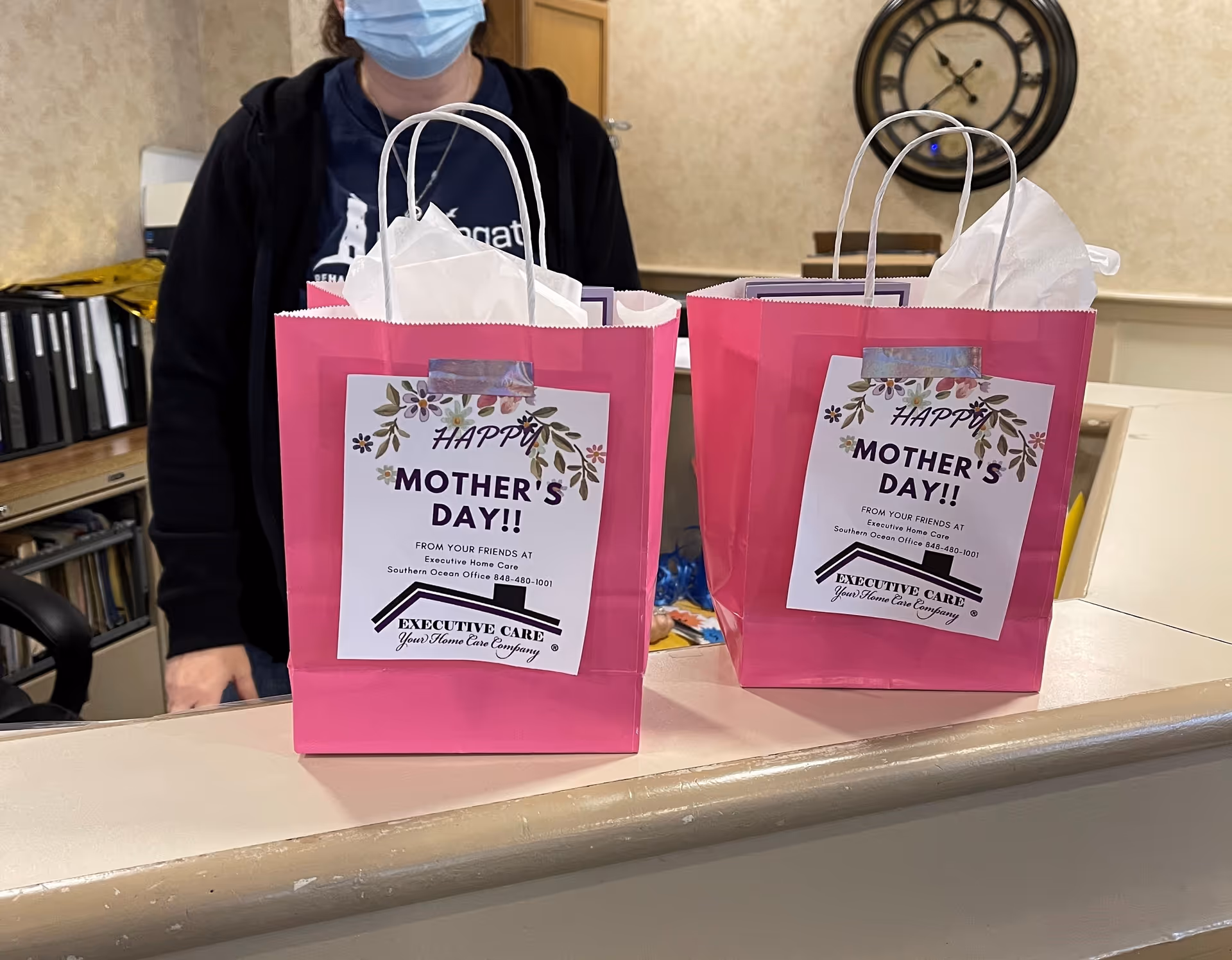 Two pink gift bags labeled Mother's Day sit on a reception counter.