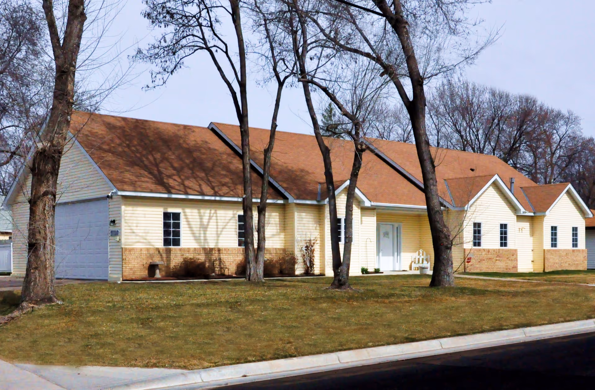 Front view of Homeward Bound Inc senior living facility with trees.