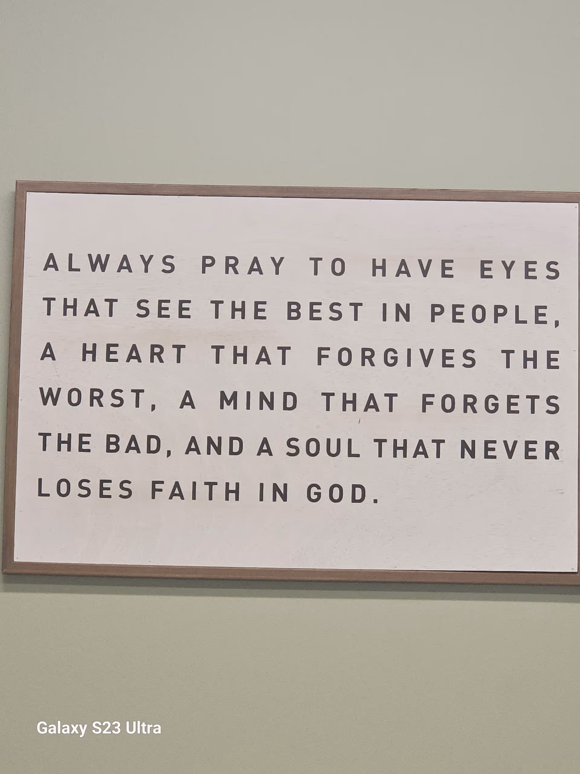 Framed inspirational quote sign on a light green interior wall in a facility