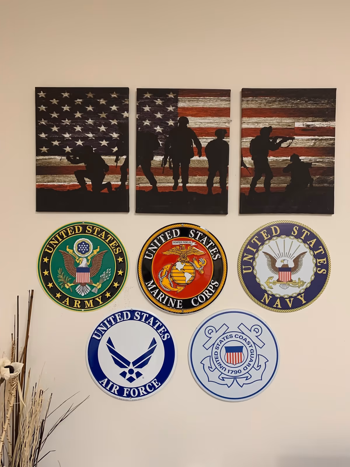 Three-panel flag artwork above circular United States service emblems on wall.