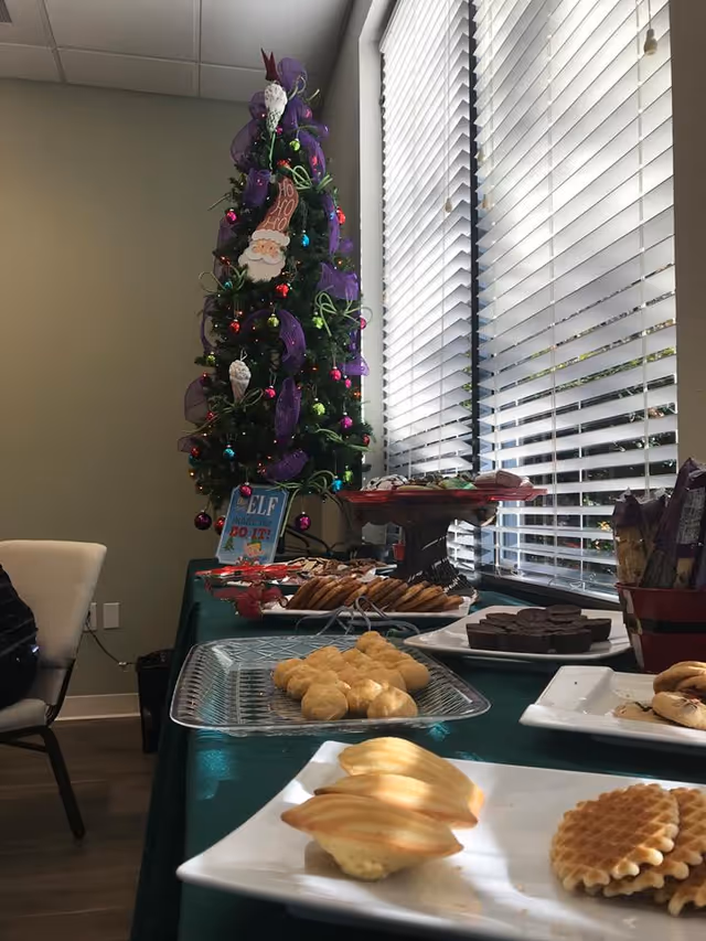 Interior communal area with a decorated Christmas tree beside a snack buffet.
