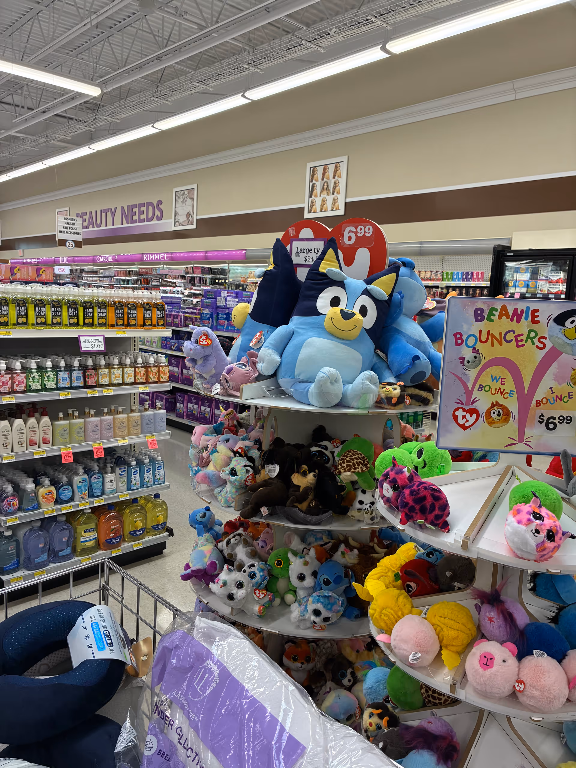 Bright drugstore aisle filled with colorful plush toys and beauty products on shelves.
