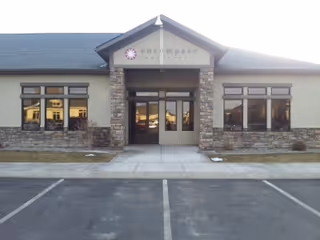 Front view of a stone-accented facility entrance with glass doors and a parking lot