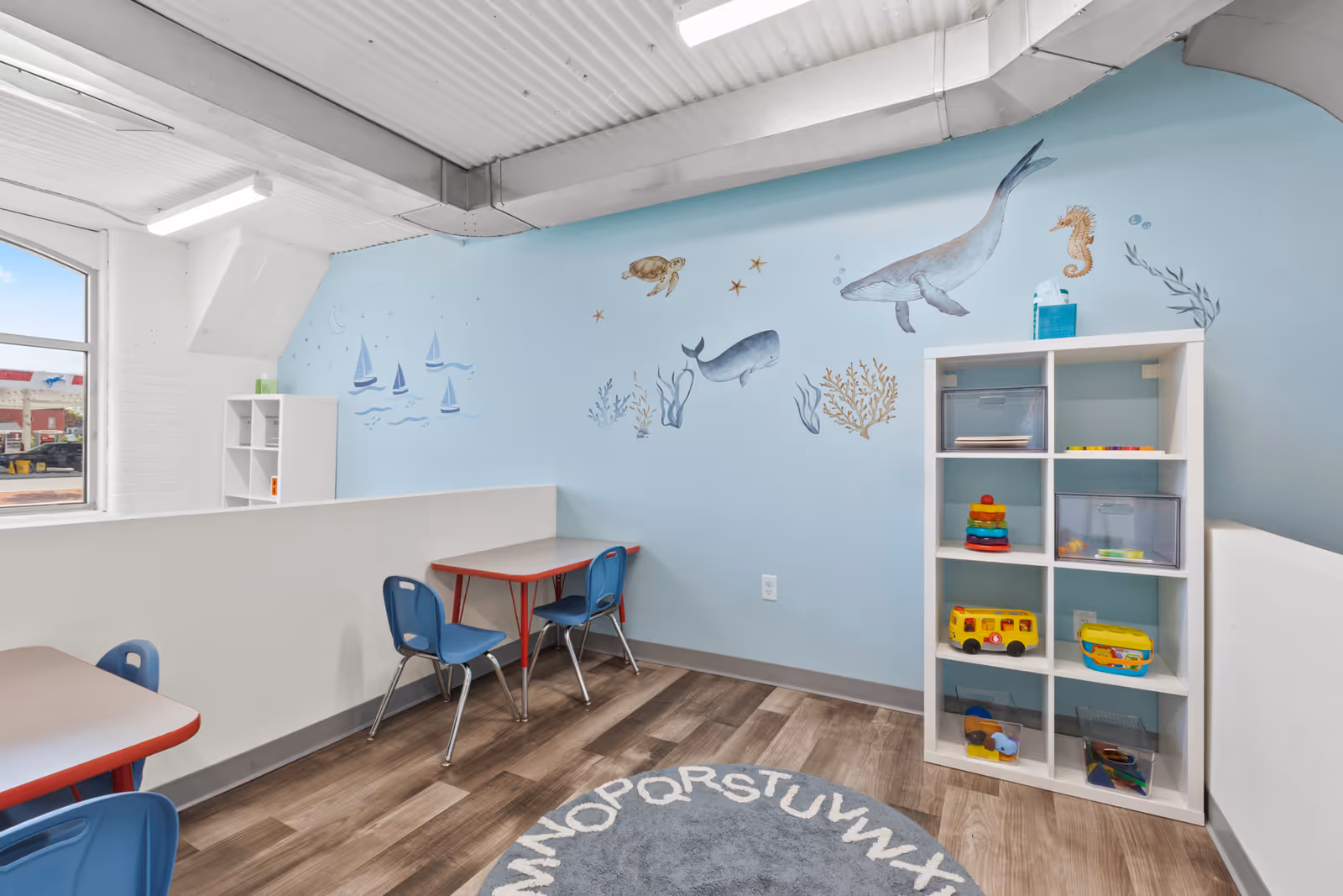 Bright, child-friendly playroom in a senior facility with murals and toy shelves.