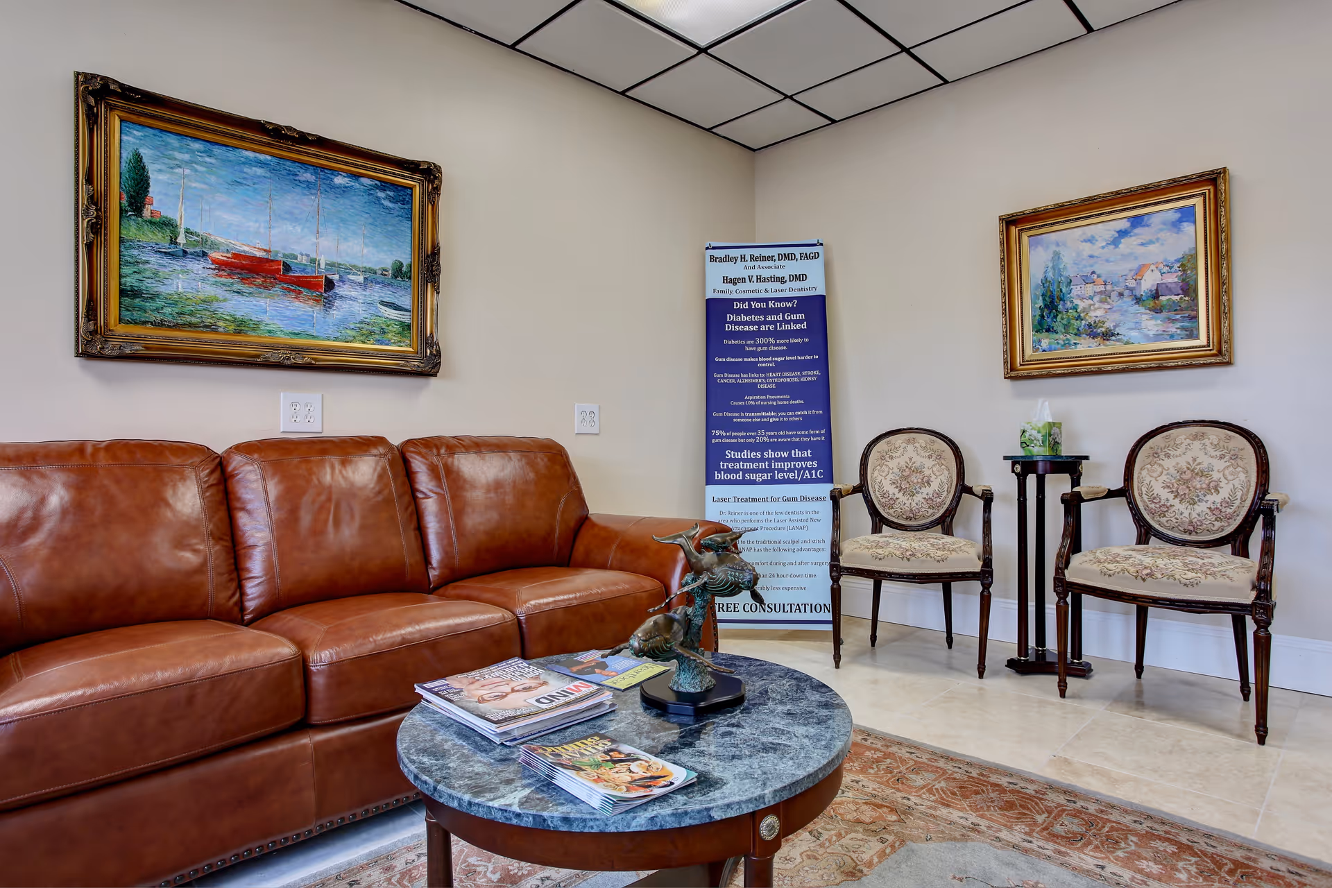 A waiting area with brown leather sofa, chairs, coffee table, and a banner in a foyer