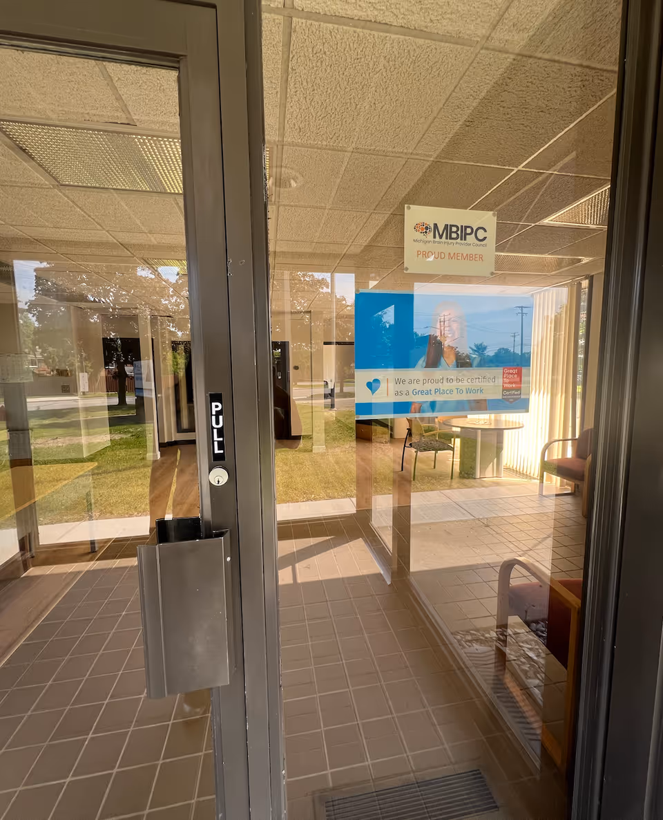 Glass entry doors lead into a tiled lobby with seating and posters.