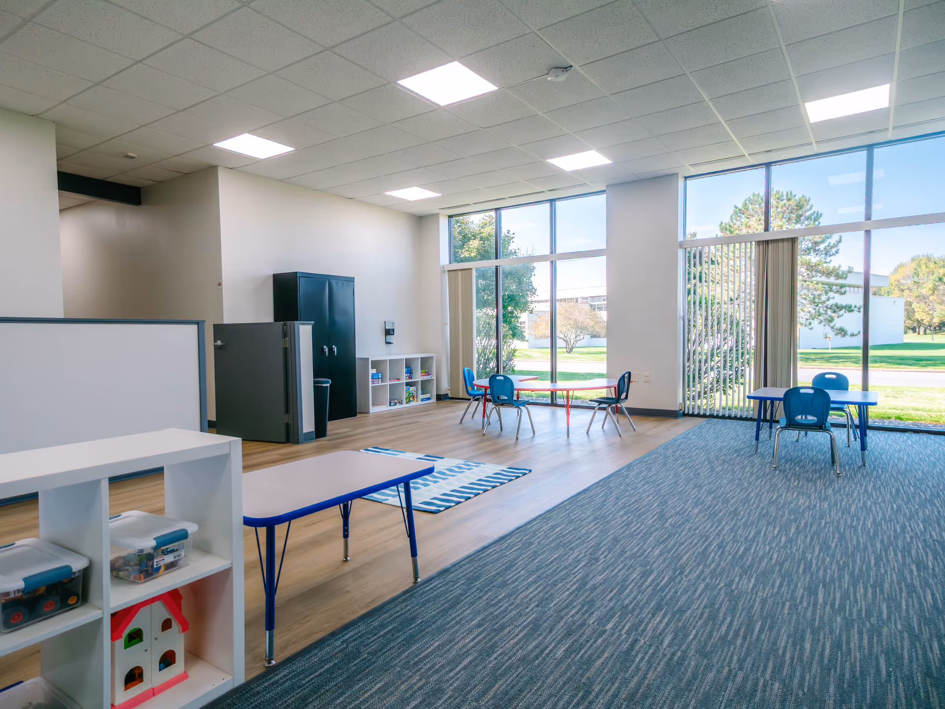 Bright, spacious interior playroom with child-sized furniture, shelves, and large windows.