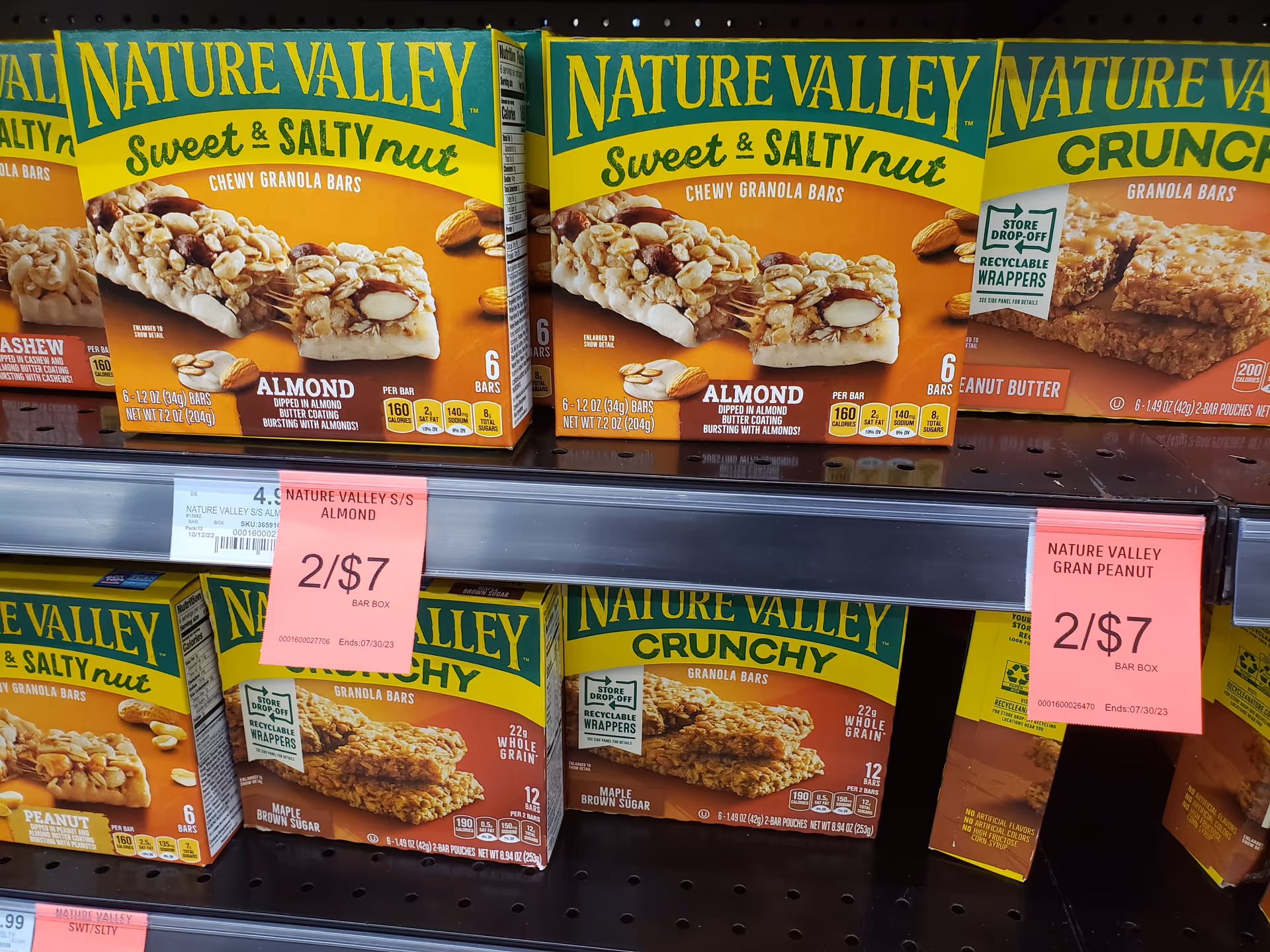 Colorful Nature Valley granola bars on store shelves with pink sale tags.
