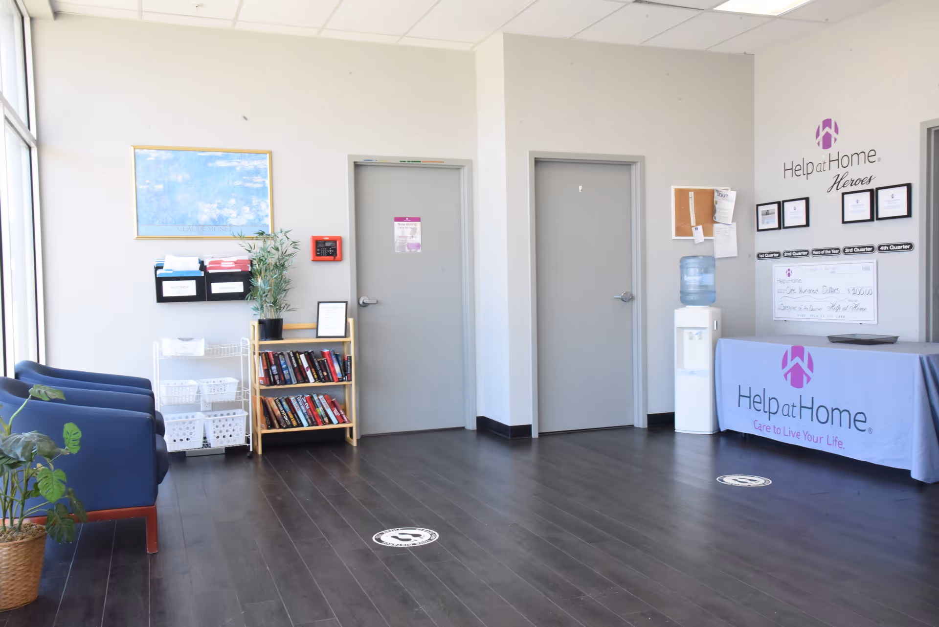 Lobby reception area of Help at Home with seating, bookshelf, water cooler, and doors.