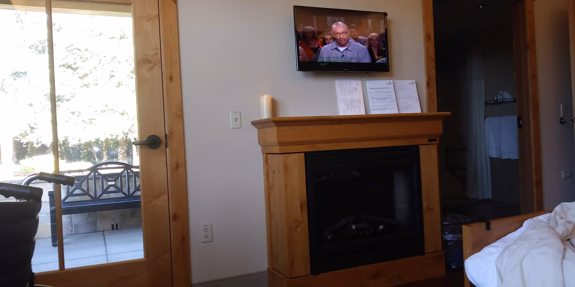 Interior living room with a wood fireplace, wall-mounted TV, doorway to patio, and walker nearby.