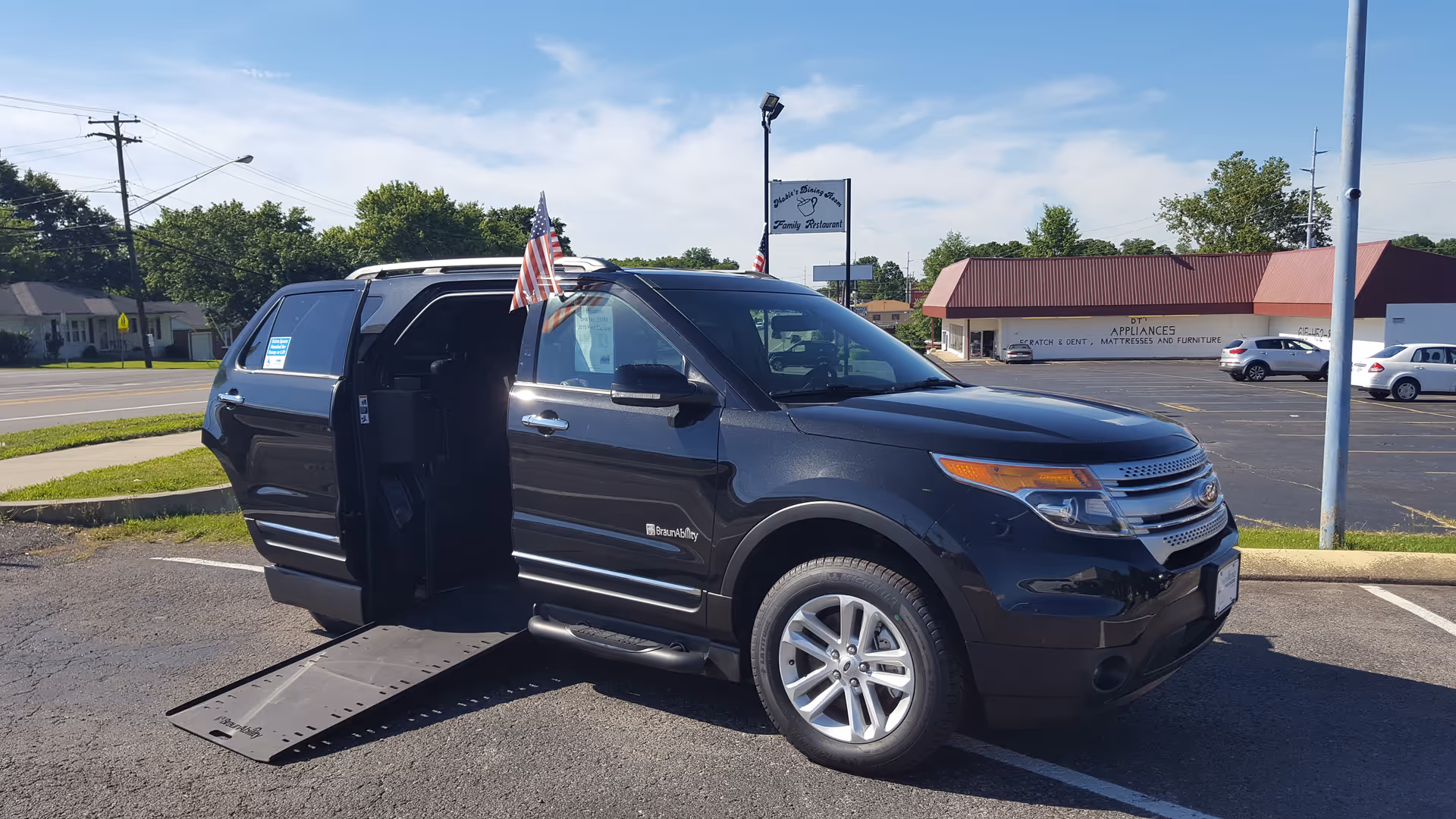 Black wheelchair-accessible van with deployed ramp in parking lot
