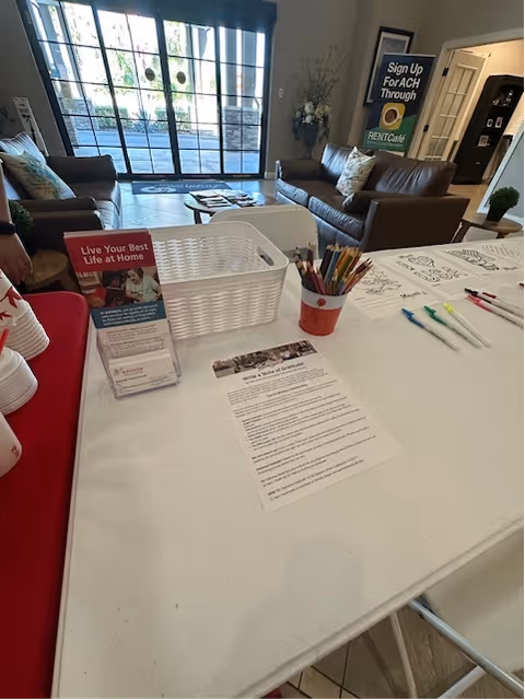 Front desk with forms and supplies in a BAYADA Assistive Care lobby; seating area beyond.