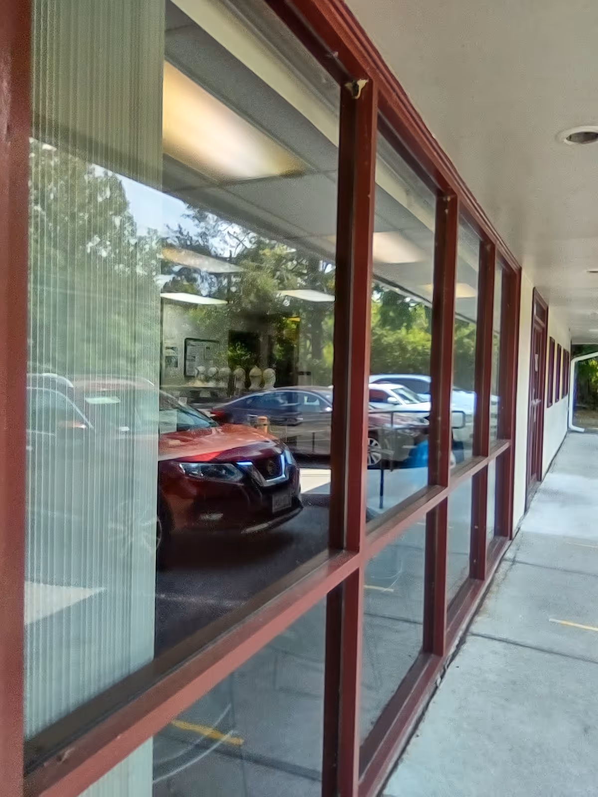 Exterior view of a LINCARE facility with large glass windows and parked cars outside.