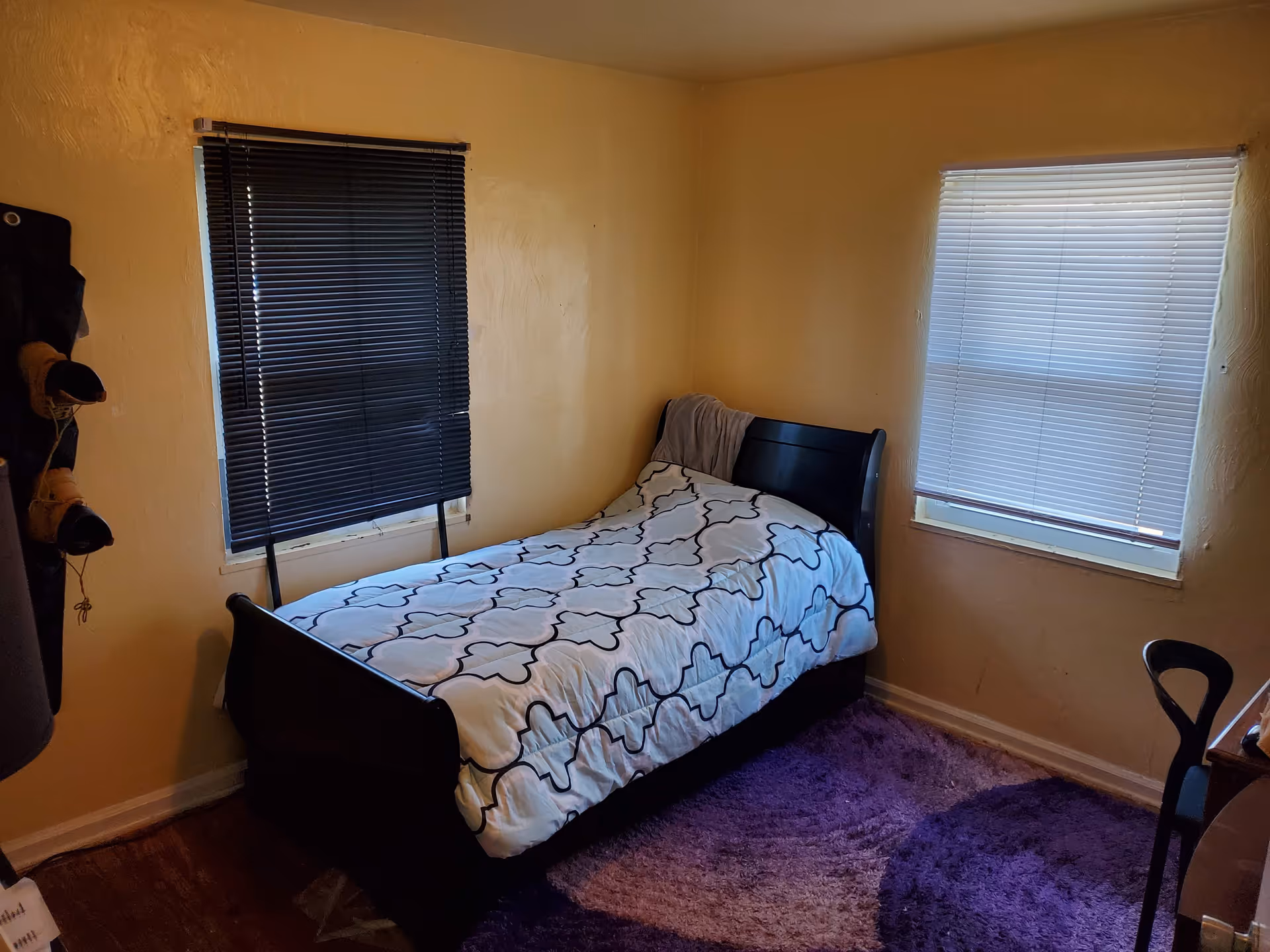 Small bedroom with a single bed, two windows with blinds, and a purple rug.