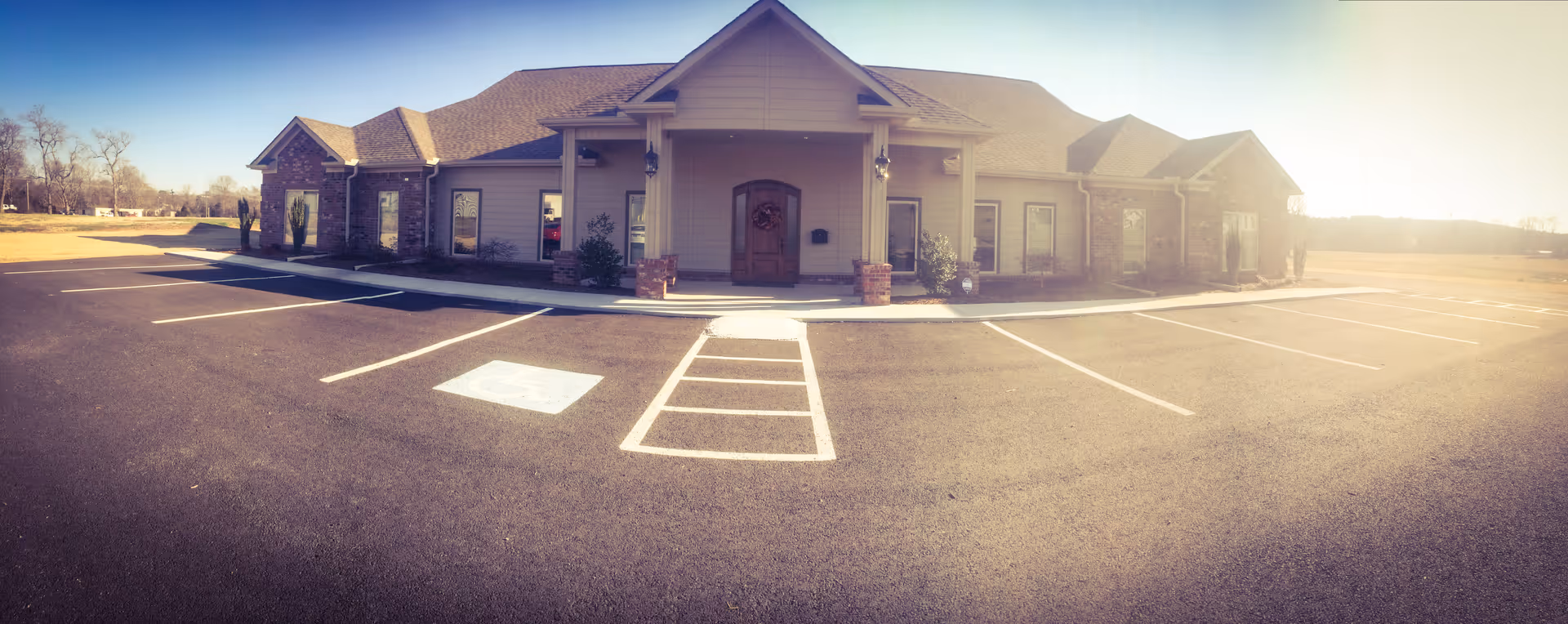 Panoramic exterior of a single-story senior care facility with a spacious parking lot.