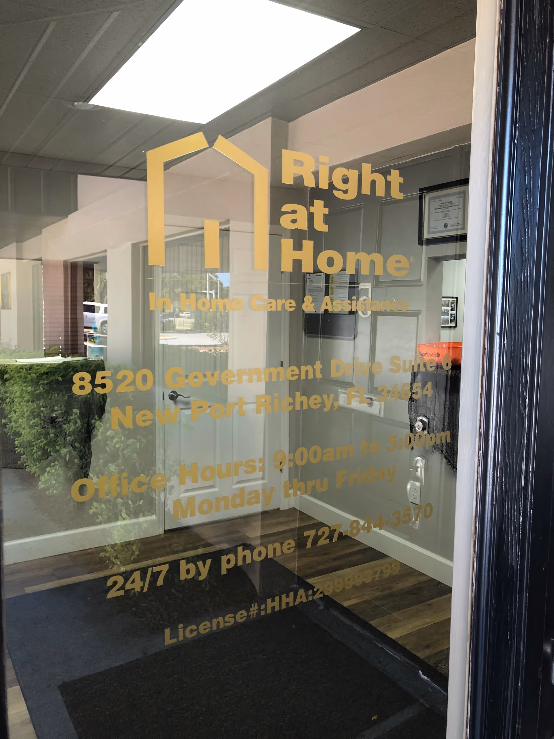 Glass door displaying Right at Home logo and address, reflecting an interior lobby.