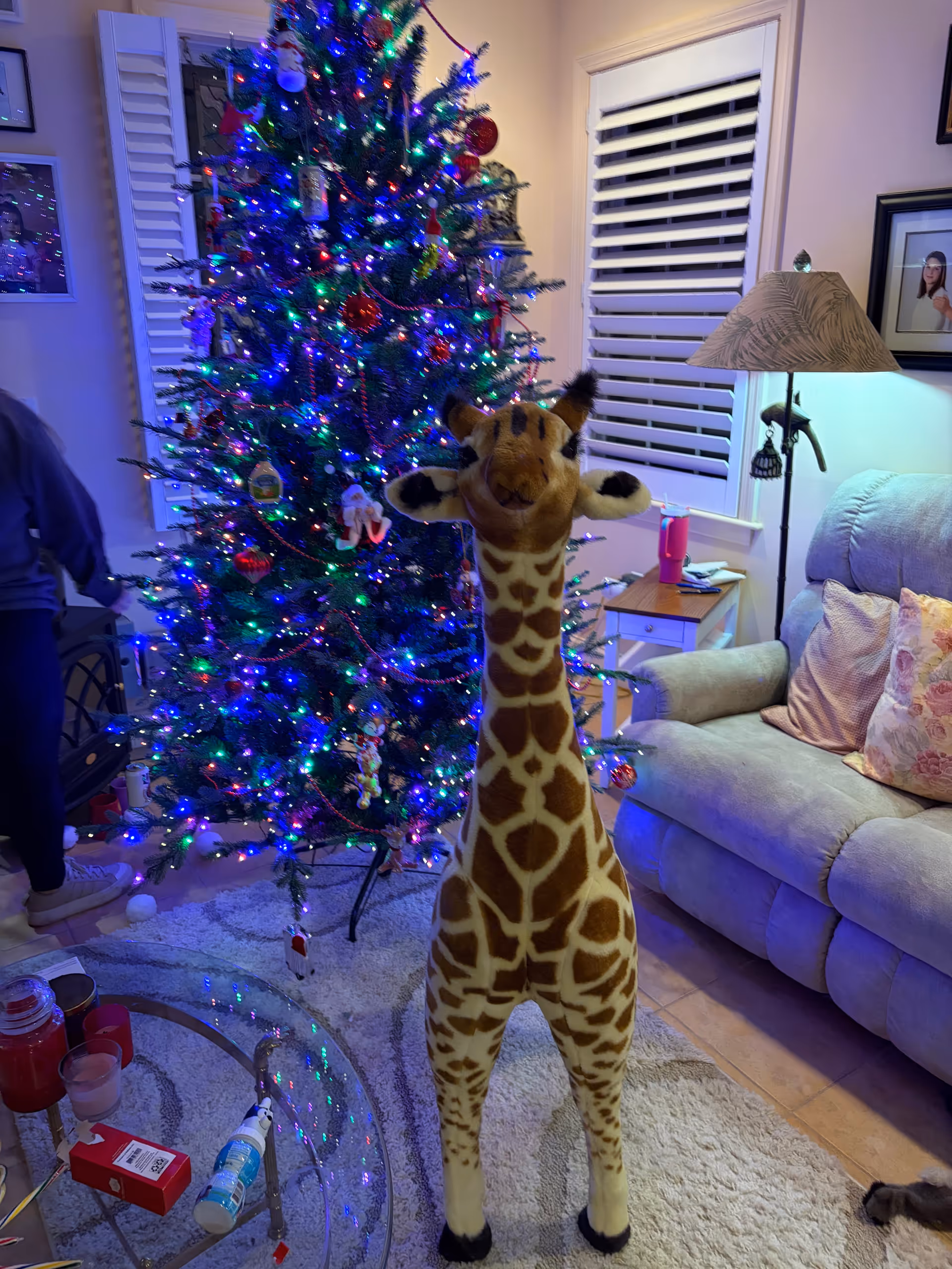 Festive living room with a tall Christmas tree, giraffe statue, and cozy seating.