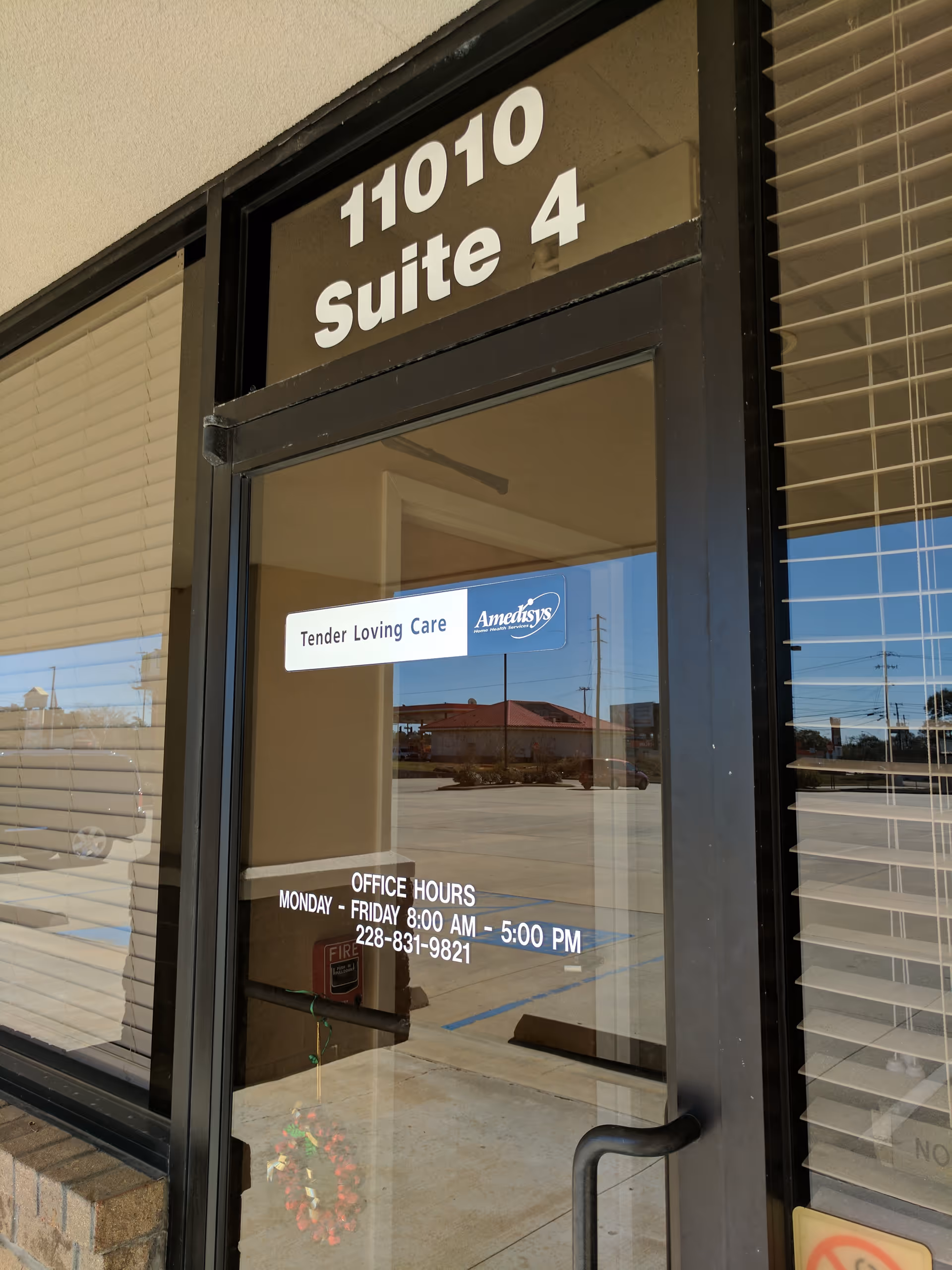 Glass entrance door displaying suite 11010, Tender Loving Care sign, Amedisys logo, and office hours.
