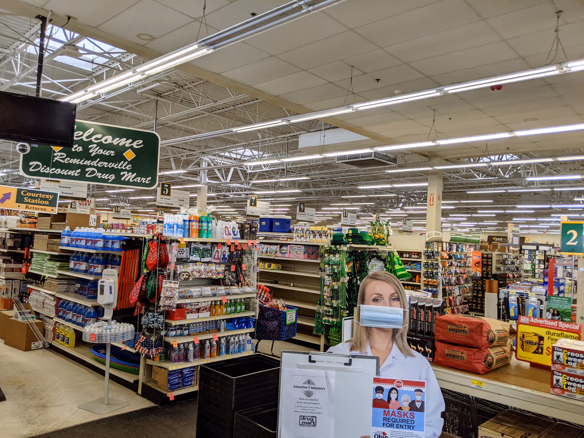 Inside a Discount Drug Mart store with aisles, shelves, and a masked promotional cutout.