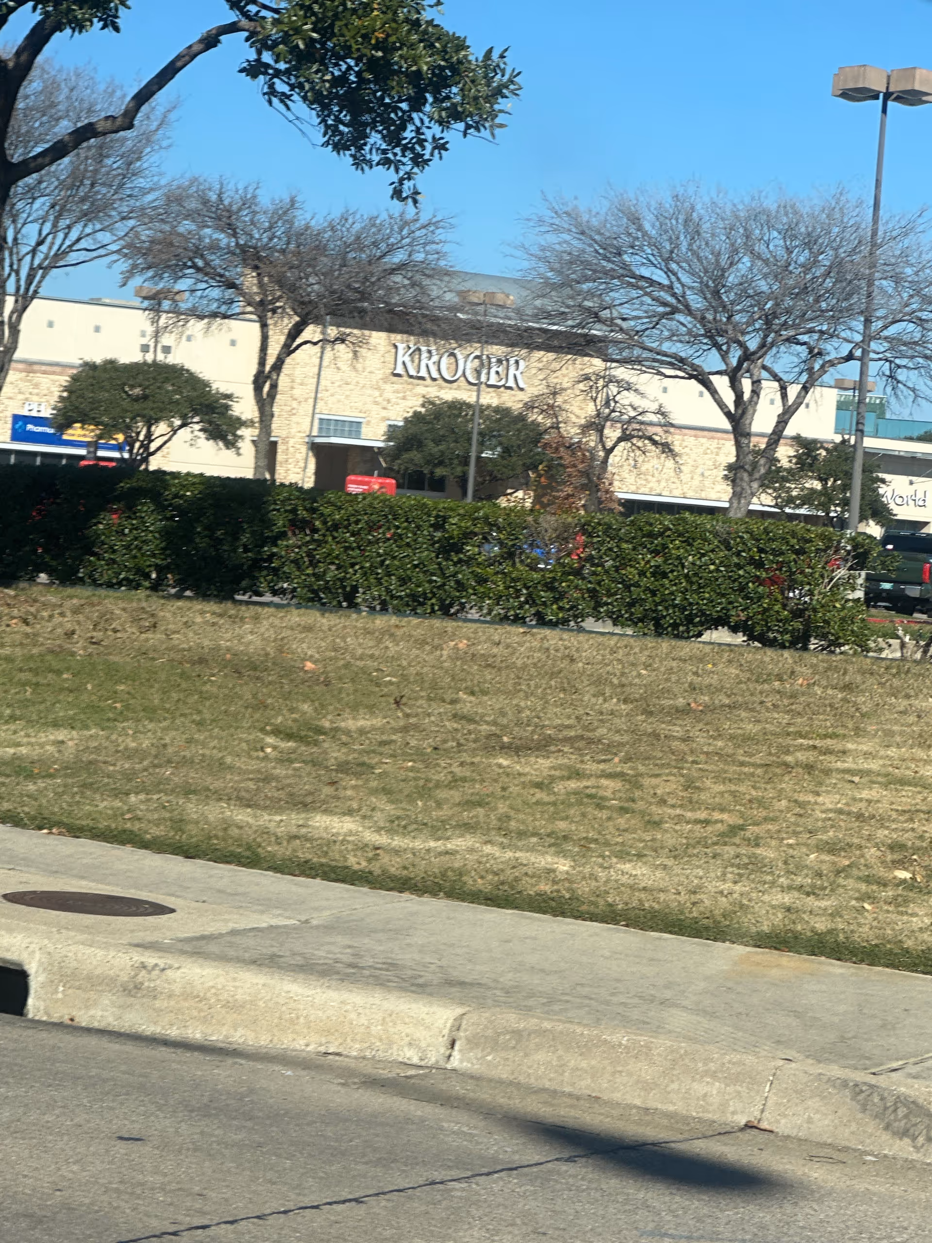 Exterior view of a Kroger store with trees and blue sky.