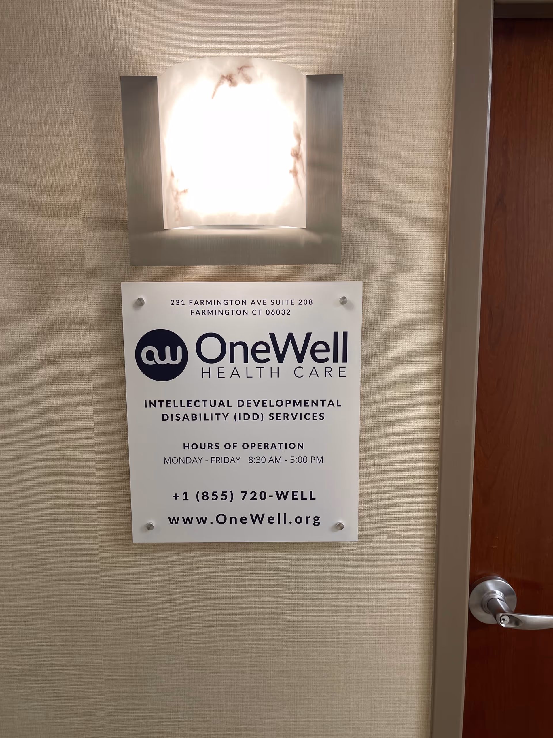 Interior wall with a lit light fixture and OneWell Health Care sign.