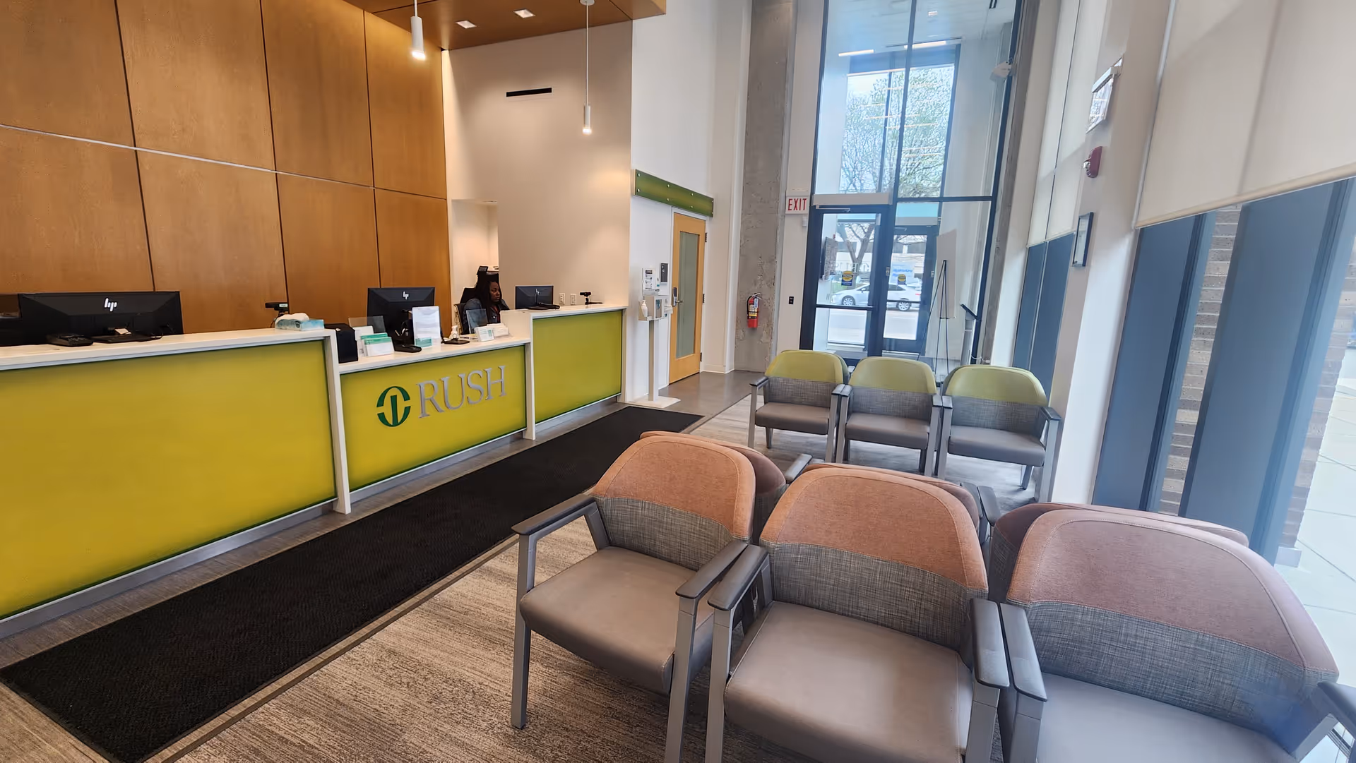 Reception area with lime-green Rush desk, seating, and glass entrance in a modern lobby.