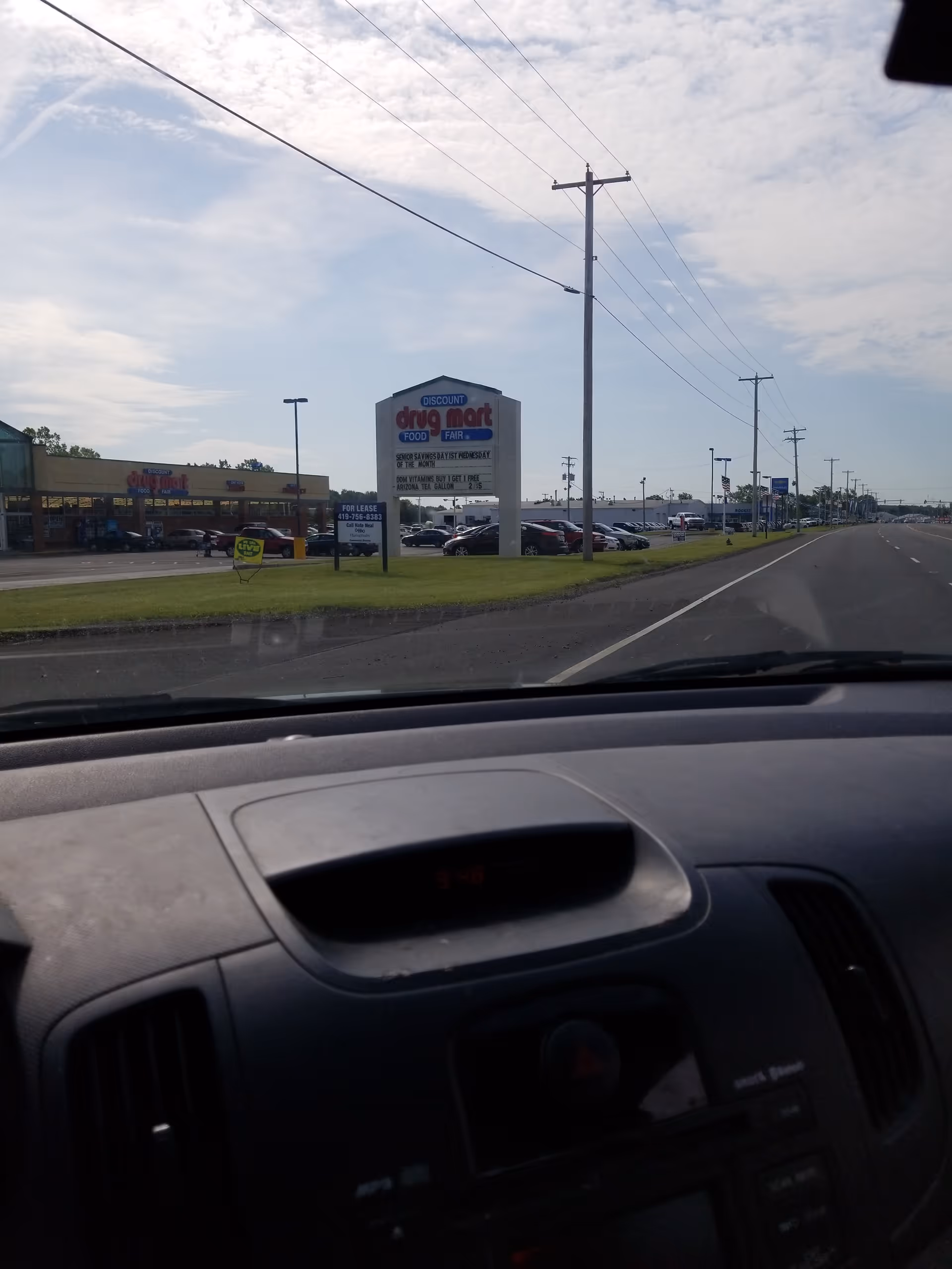 View from a car of Discount Drug Mart storefront and surrounding parking lot.