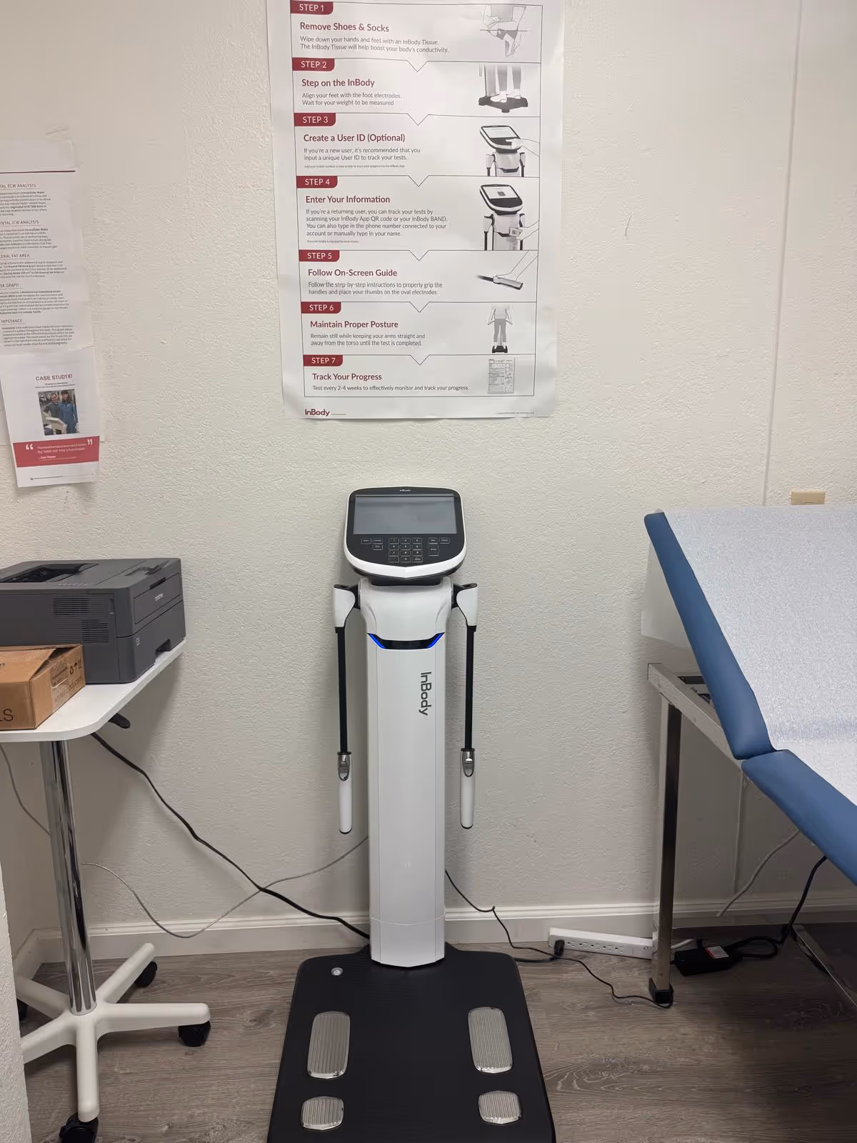 Interior medical exam room with an InBody body composition analyzer beside an exam table.
