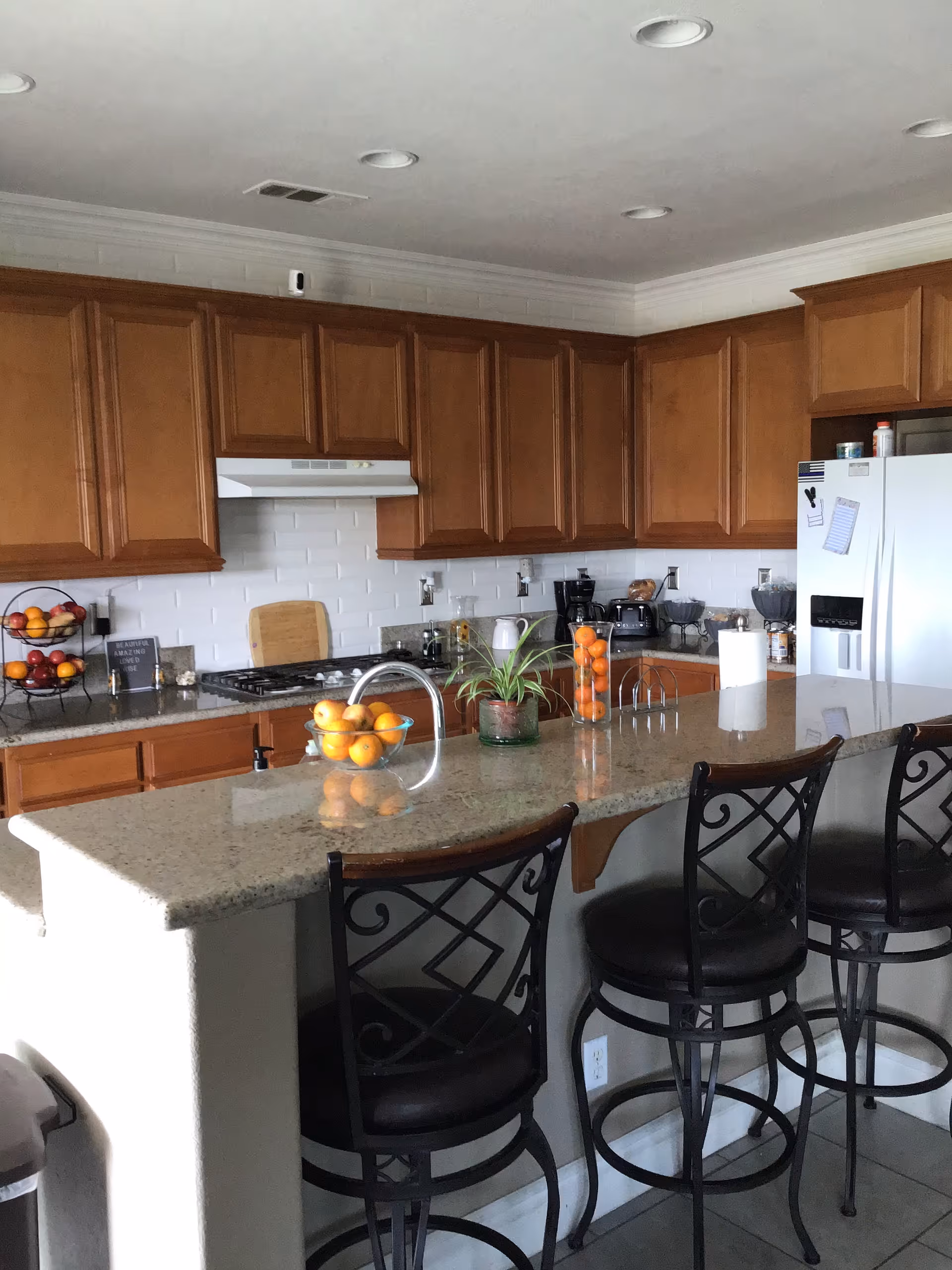 Modern kitchen with wooden cabinets, granite island, and stainless steel appliances.