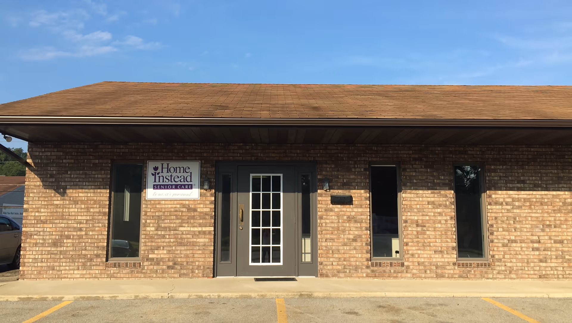 Brick building exterior with a central door, tall windows, and a Home Instead Senior Care sign.