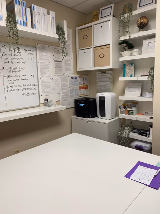 Administrative workspace in a senior care facility with whiteboard, shelves, and equipment.