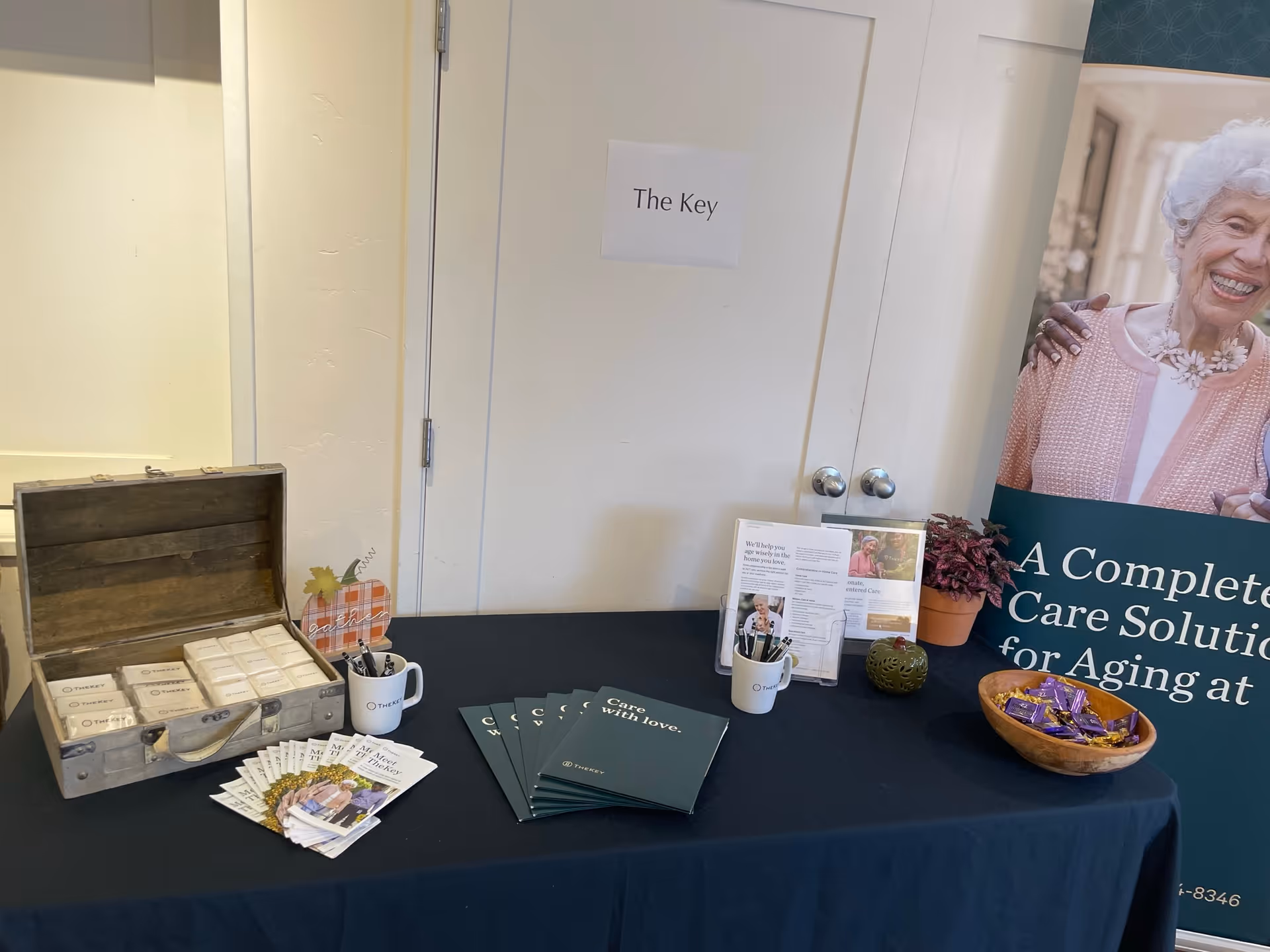 Indoor promotional display table with The Key Senior Home Care branding and brochures.