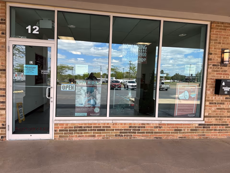 Brick storefront for Advantage Home Care with large glass windows and posters.