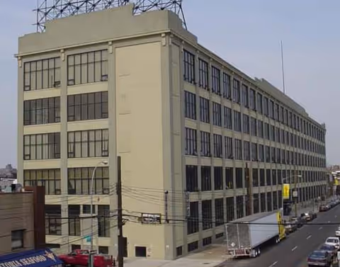 Beige, multi-story building with numerous windows facing a busy city street.