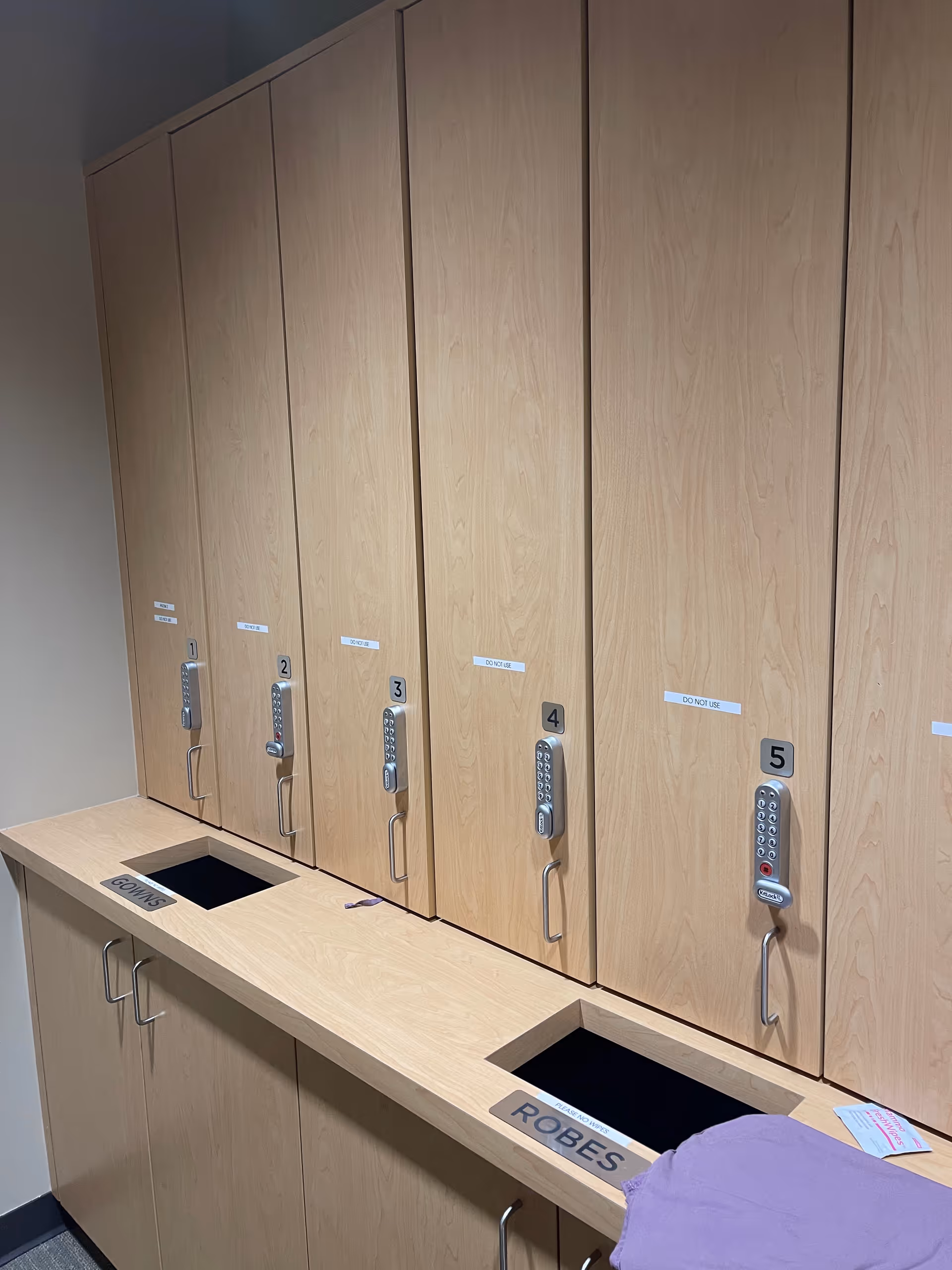 Row of wooden storage lockers with numbered locks along a counter.