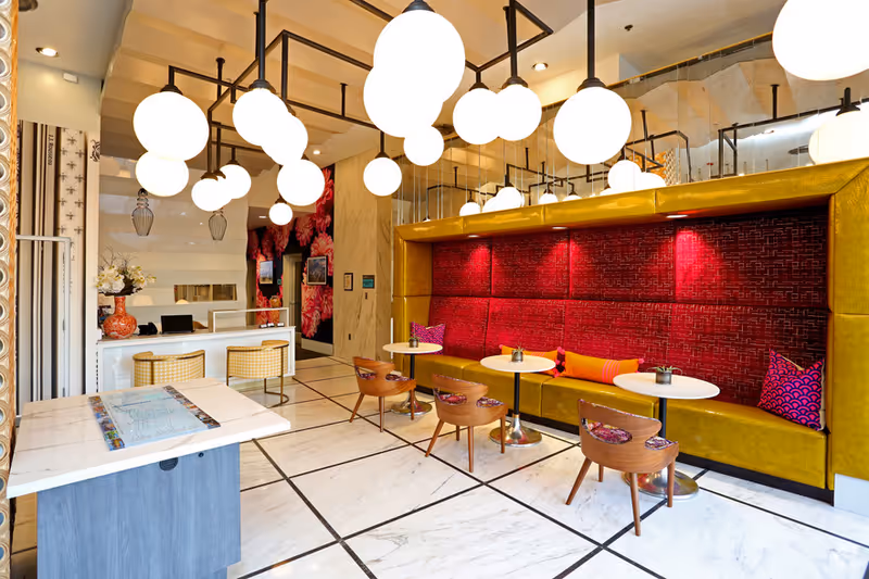 Bright modern lobby with globe pendant lights and red and yellow upholstered seating.