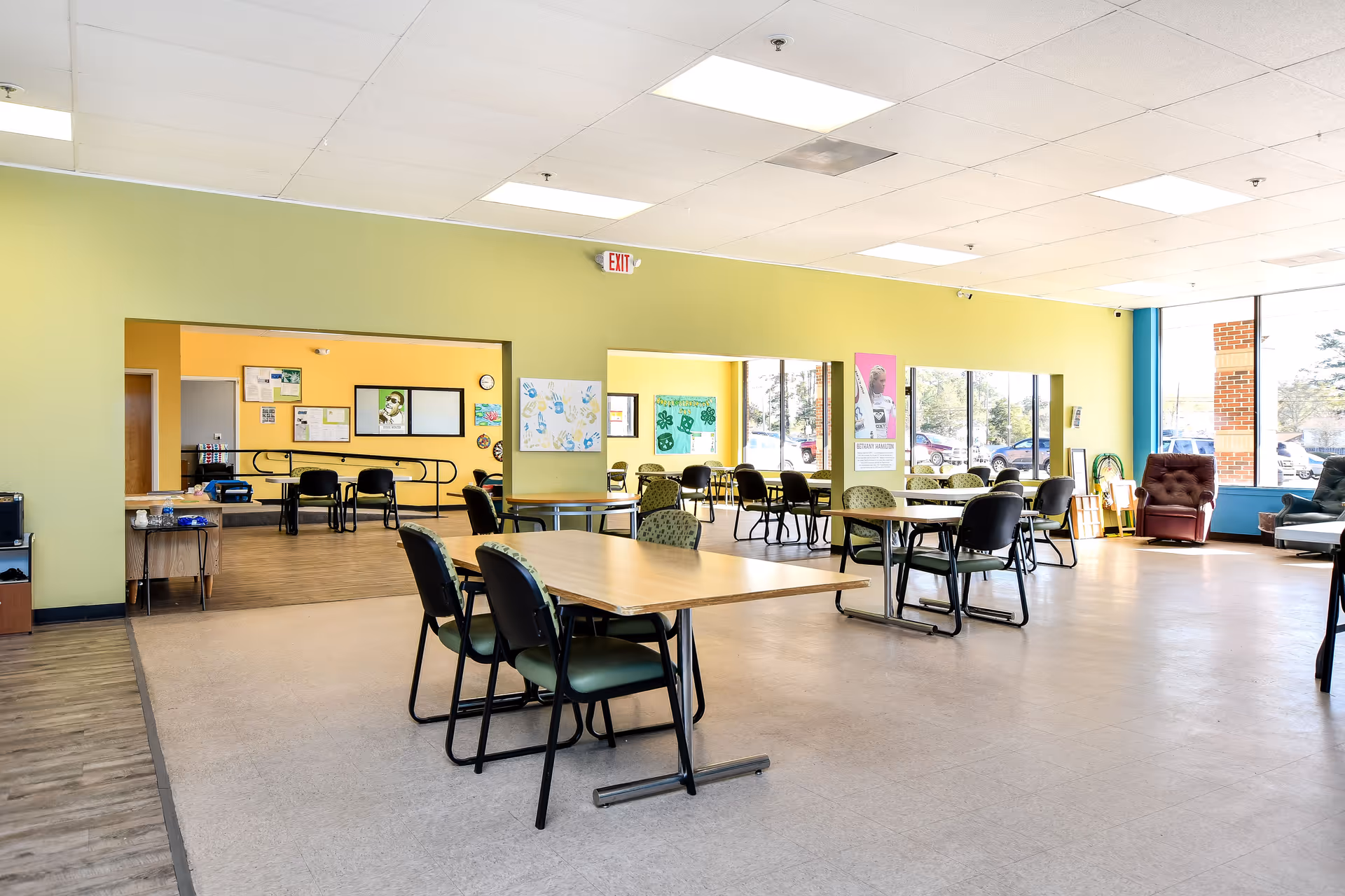Bright communal area with tables and chairs inside a senior living facility.