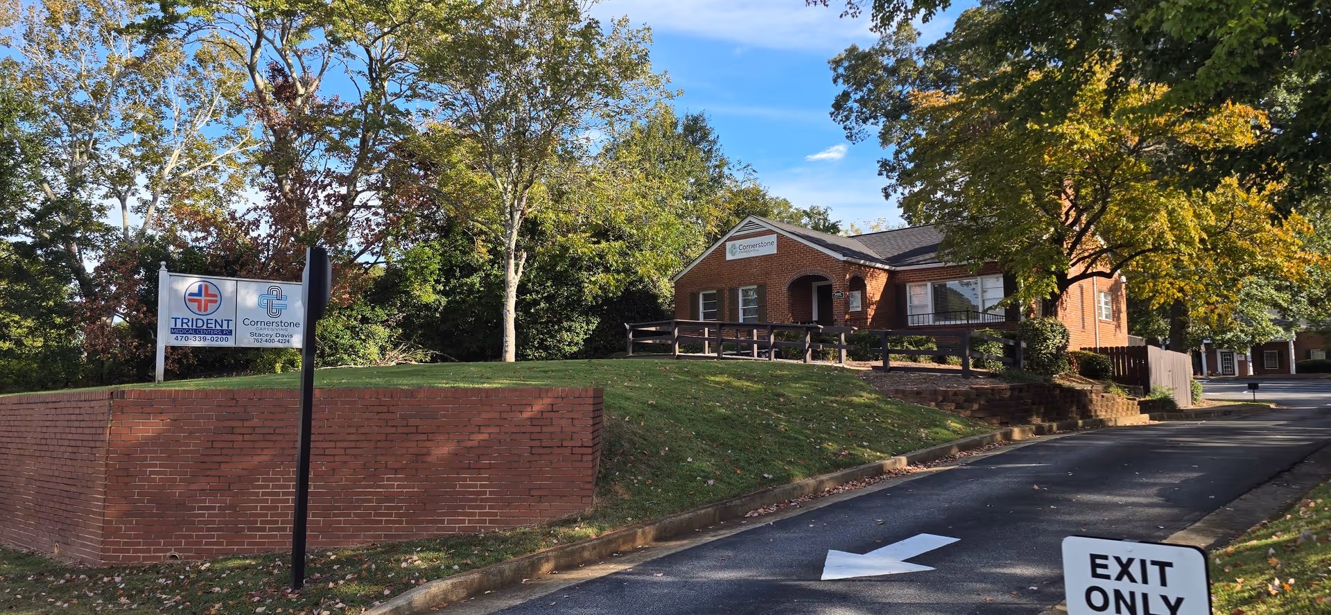 Brick senior living facility exterior with Cornerstone sign, trees, and a driveway.