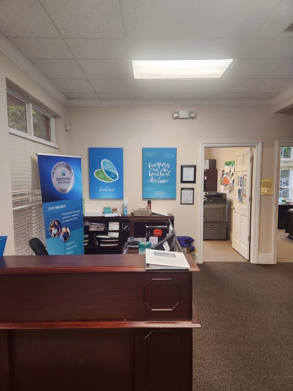 Reception area with a dark wooden front desk, blue posters, and brochures.
