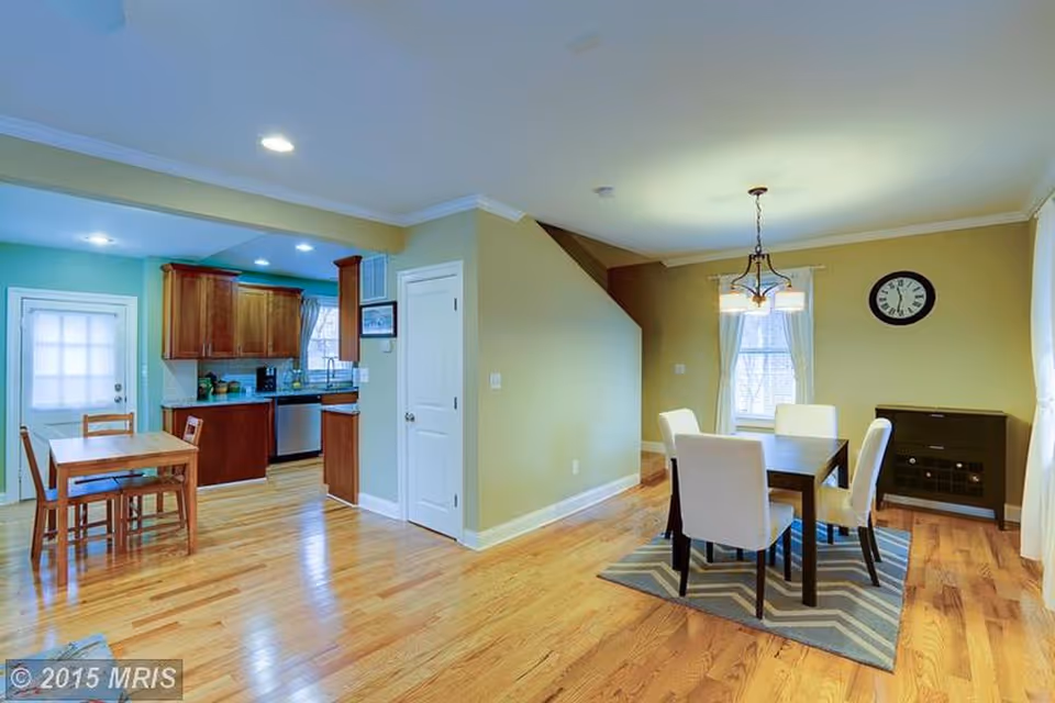 Open, well-lit dining area and kitchen with wooden floors and staircase.
