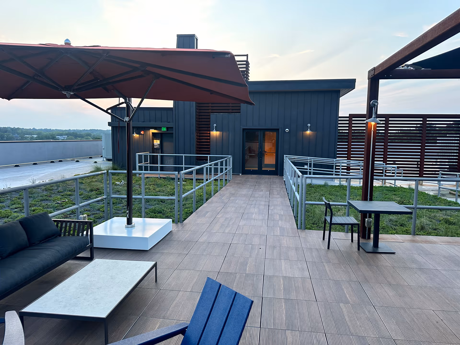 Rooftop outdoor patio with seating and umbrella beside a modern building
