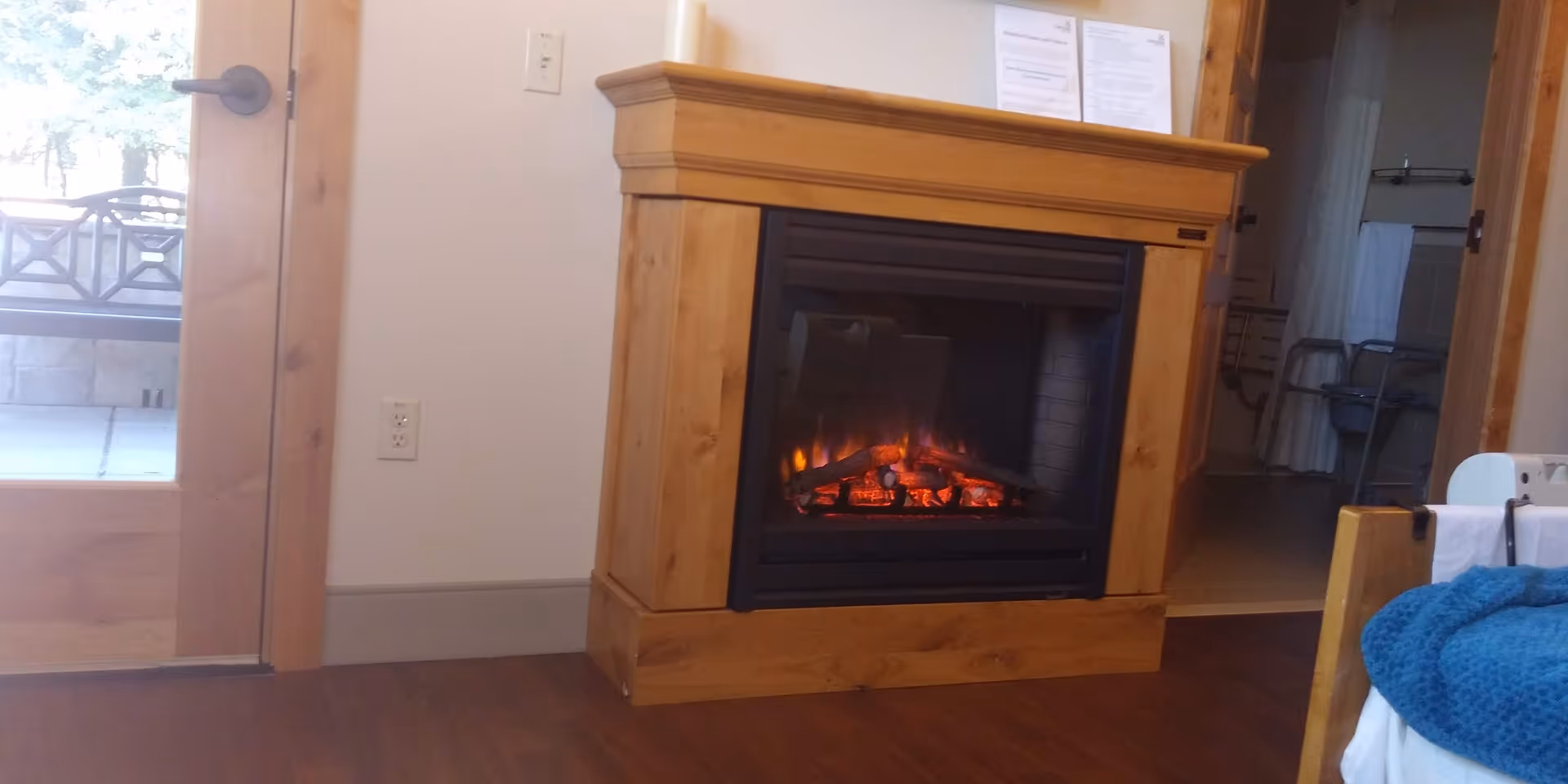 Cozy living room with a wood-burning fireplace, mantle, and hardwood floors.