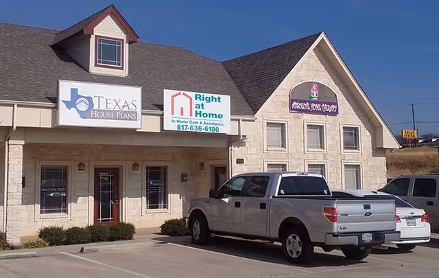 Front exterior of a Right at Home senior care building with signs and parked trucks.