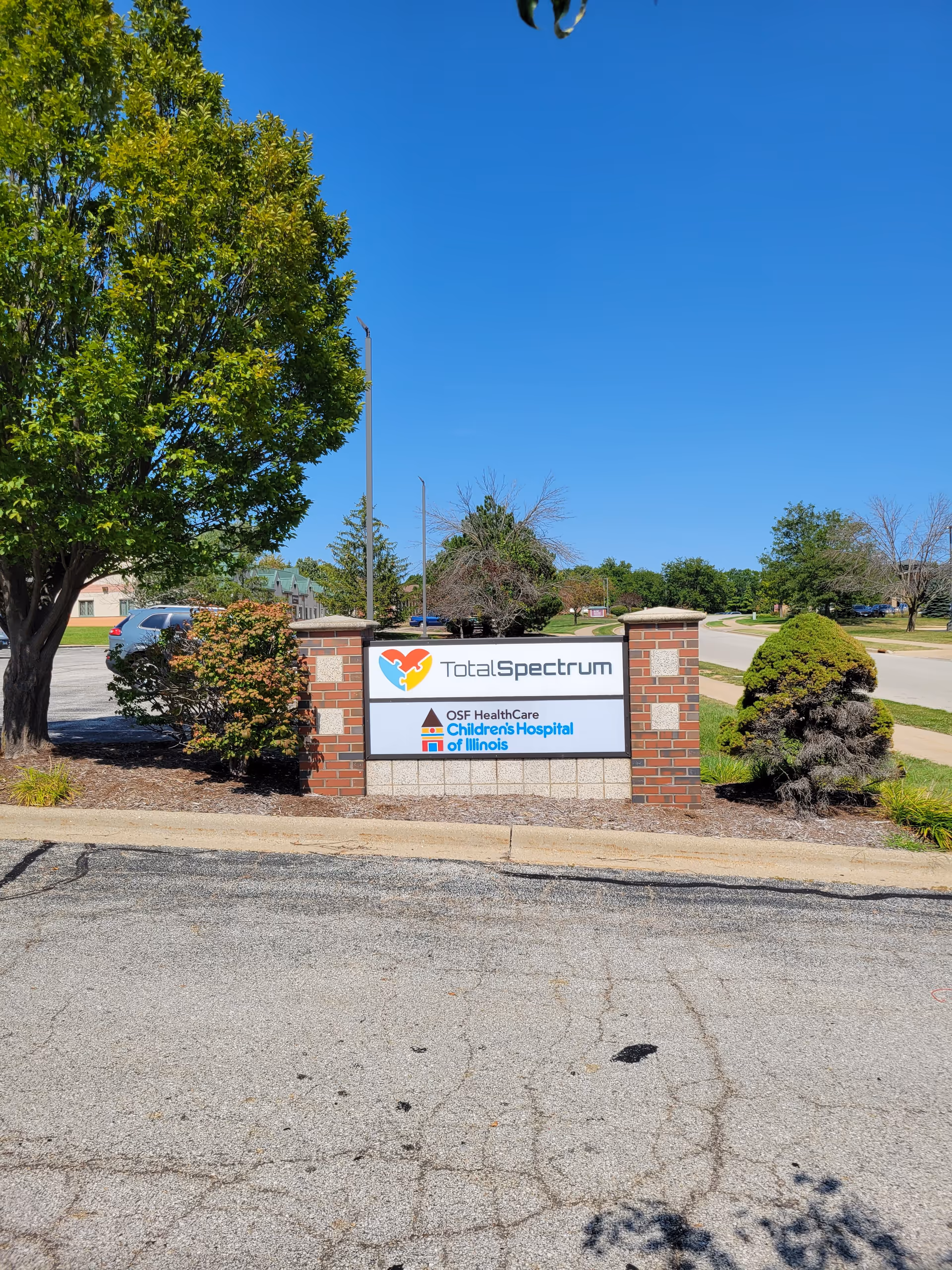Exterior sign for Total Spectrum ABA at a brick-framed entrance with landscaping.