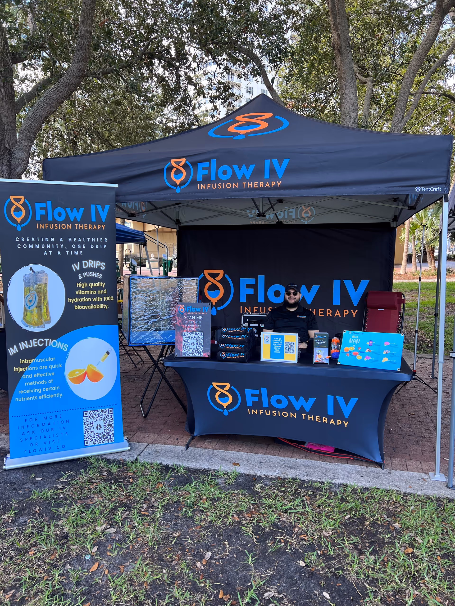 Outdoor Flow IV Infusion Therapy booth with banners and a staff member.