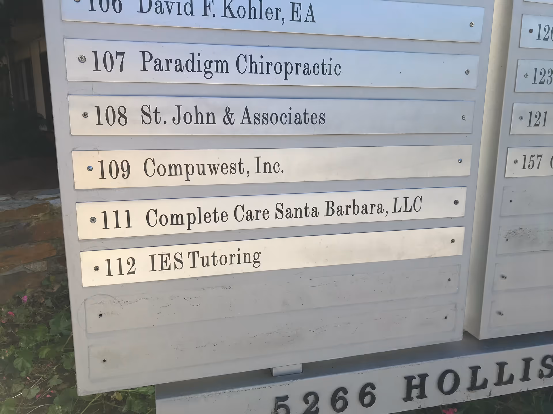 Exterior signboard listing multiple business names on a building facade