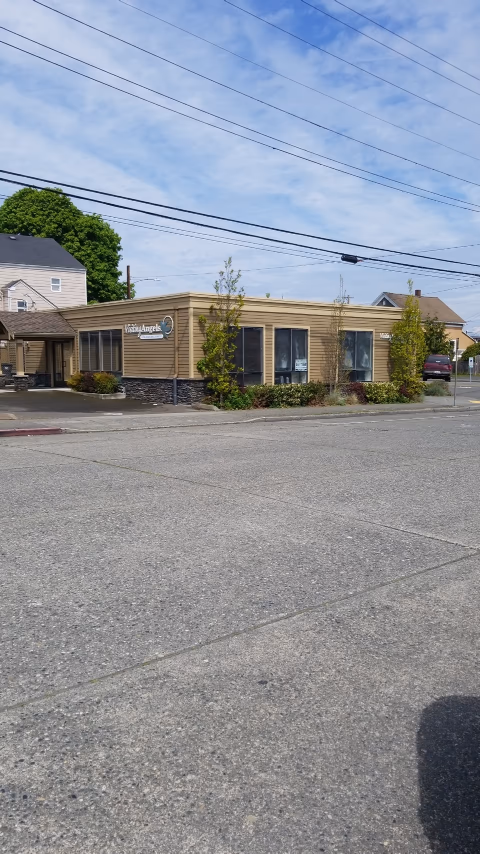 Single-story tan Visiting Angels senior home care building front with parking lot.